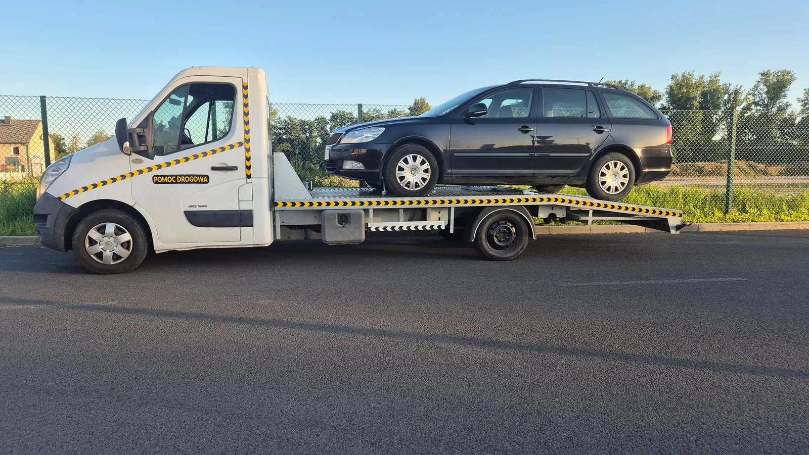 Laweta z samochodem osobowym kombi zapiętym na platformie